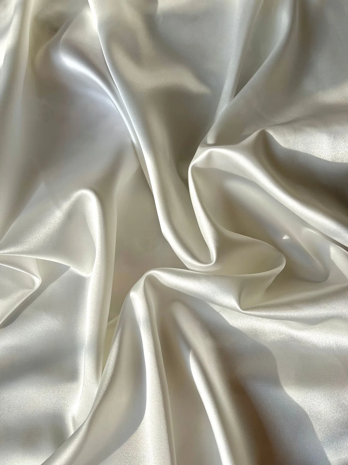 Ivory crepe satin folds showing fine pebbled crepe texture and soft luster