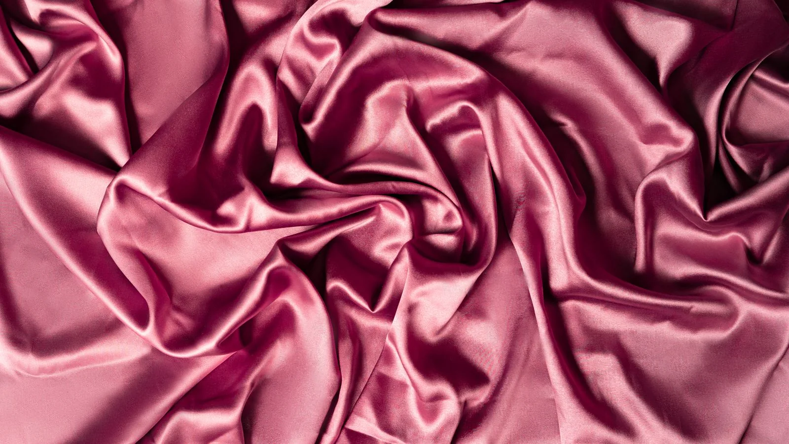Draped rose-pink crepe satin fabric showing its glossy satin face