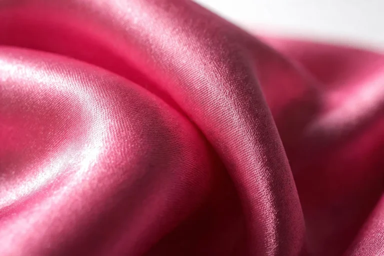 Extreme macro of pink satin weave with light raking across long warp floats showing mirror-like reflection